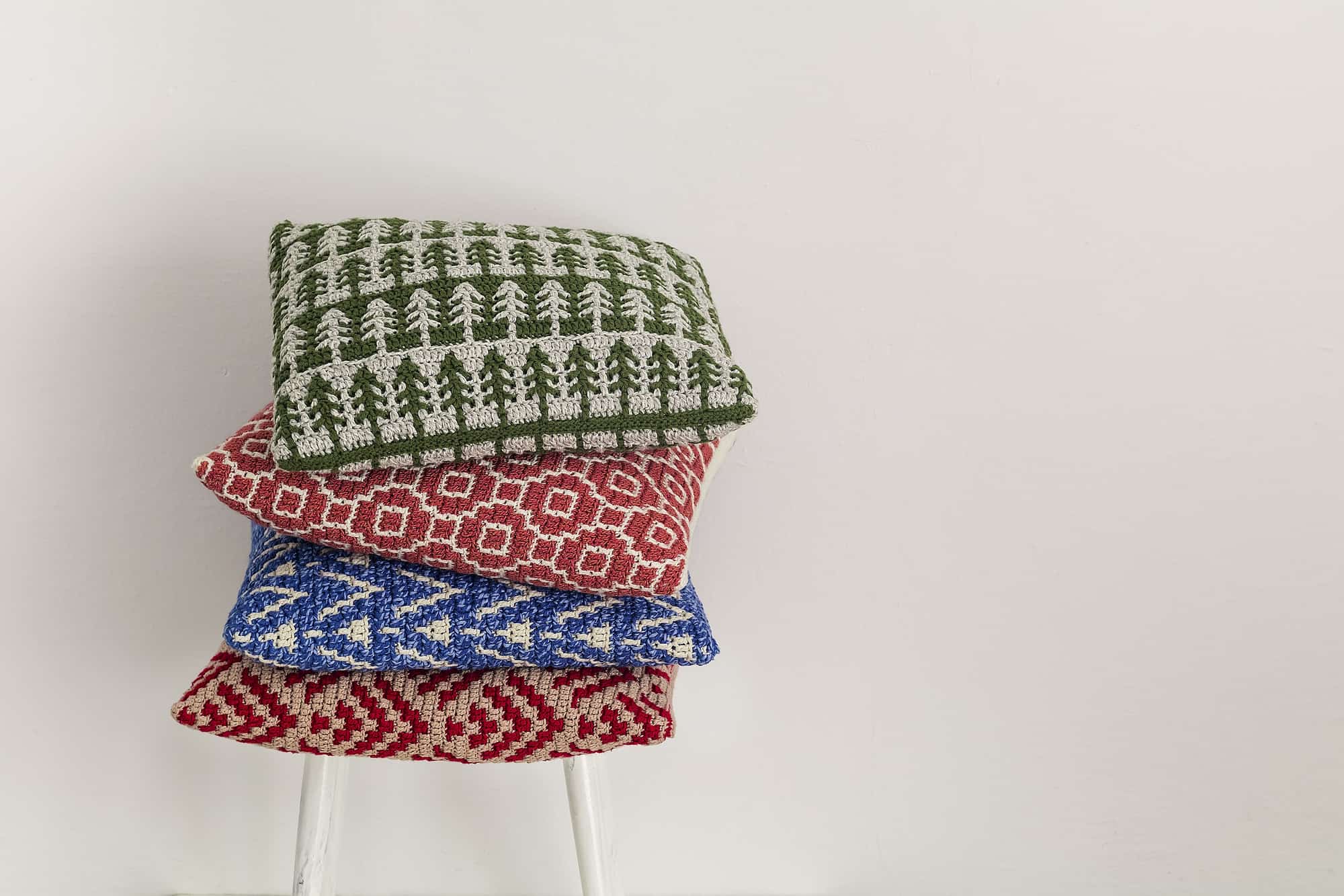 Erik Hansen Crochets for ADHD … and Profits: 10 Examples 3 Stack of four colorful crochet pillow on a chair on a white background