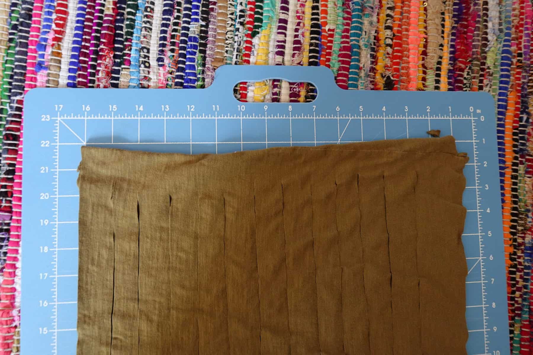 a beige t-shirt cut into strips lies on a measuring board