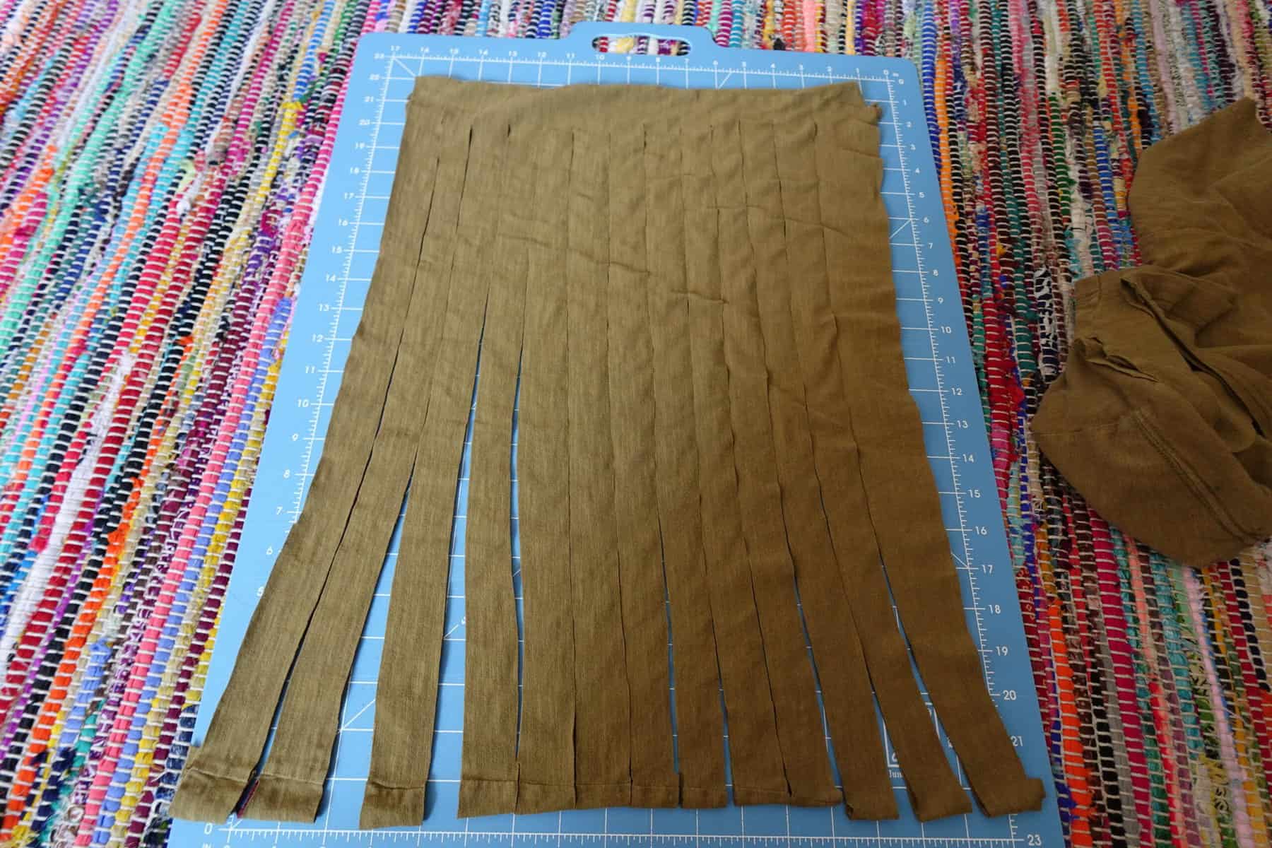 beige t-shirt cut into strips lies on a blue measuring board