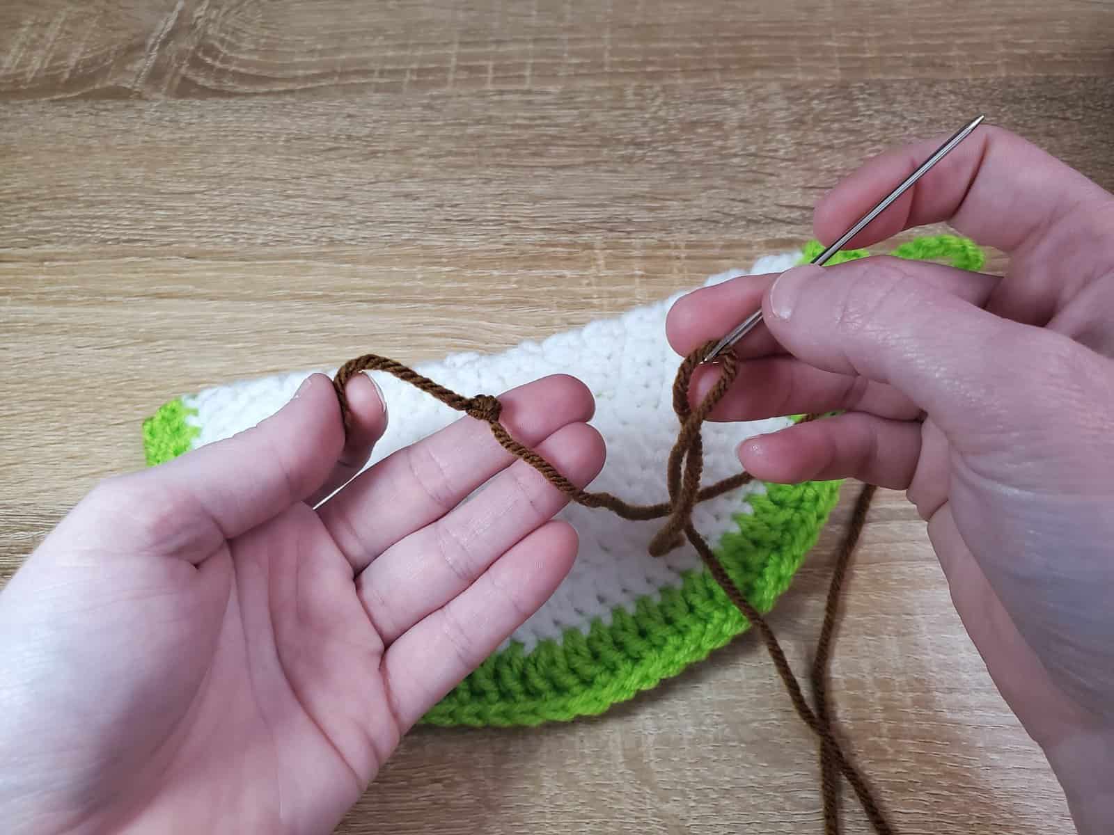 tying a knot at the end of the brown yarn
