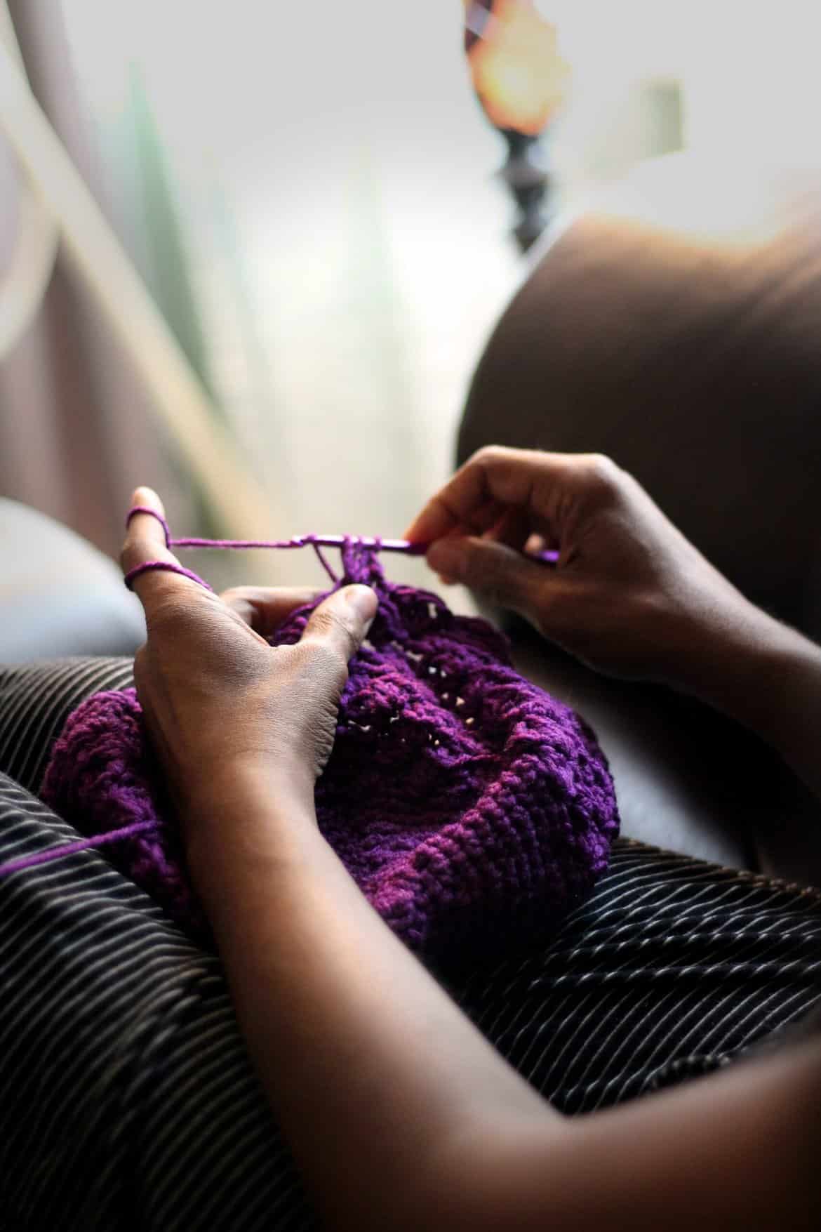 A Woman Relaxing While Crocheting with Purple Yarn