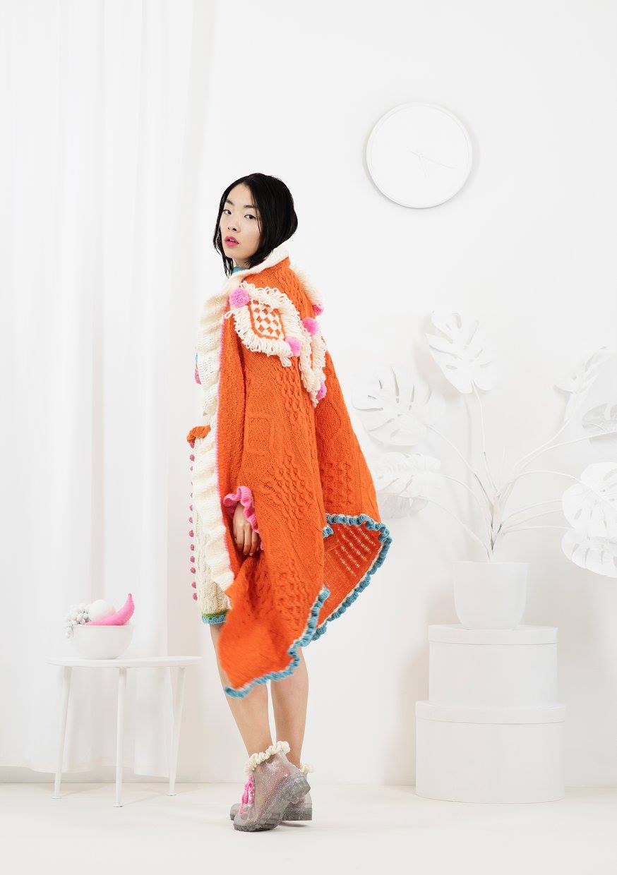 Asian model posing in orange crochet  "LET THEM EAT CAKE" collection by Katie Jones