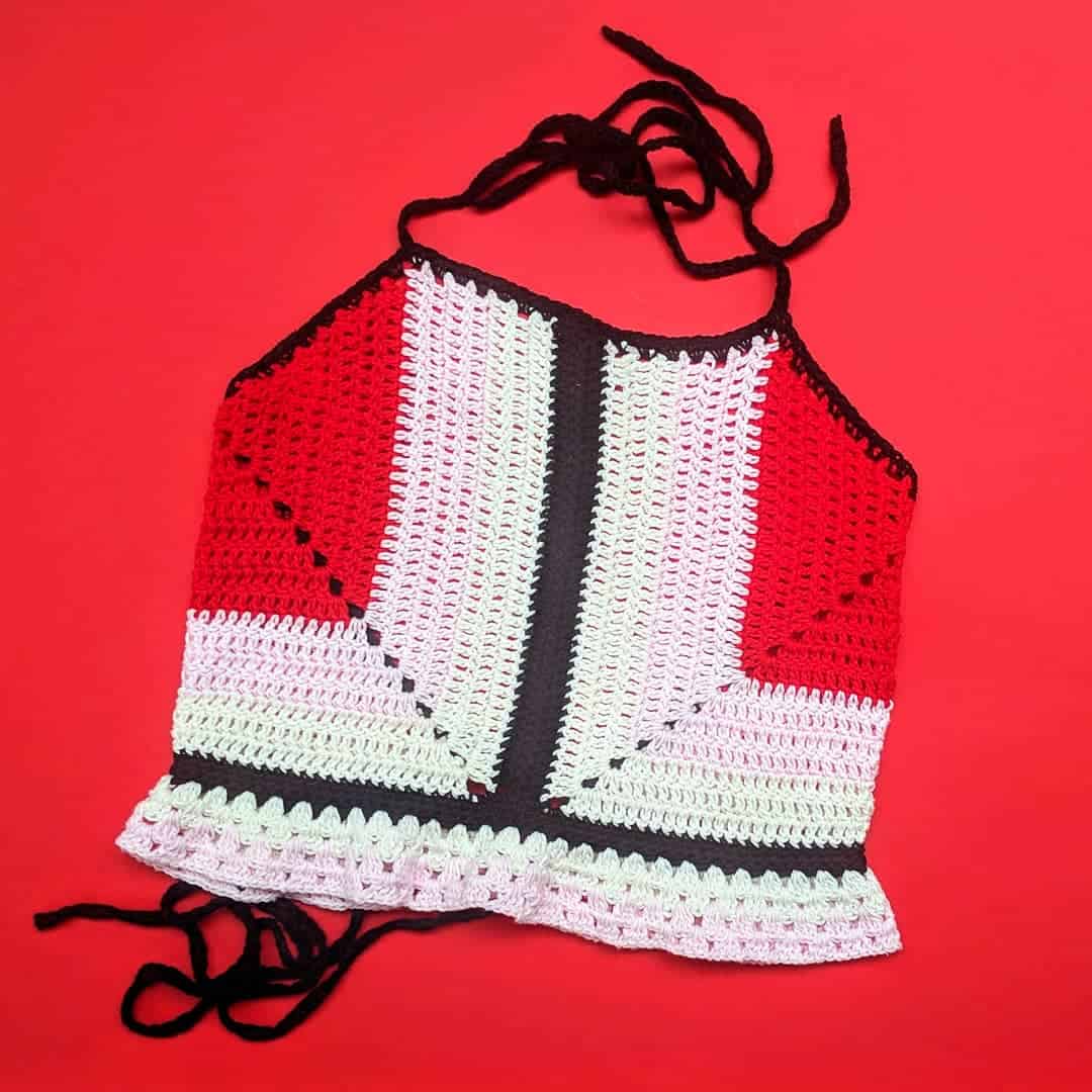 Crocheted red and white top with black elements on a red background
