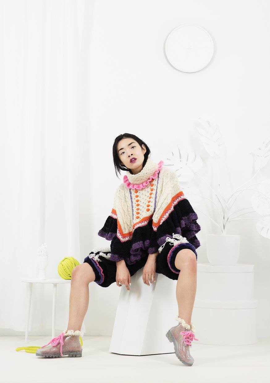 An Asian model sits in a crochet outfit of  "LET THEM EAT CAKE" collection by designer Katie Jones