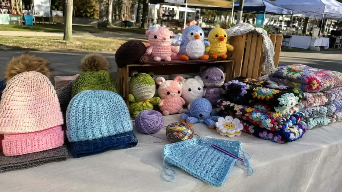 Handmade crochet items displayed on a farmers market booth table