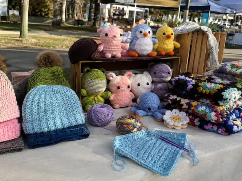 Handmade crochet items displayed on a farmers market booth table